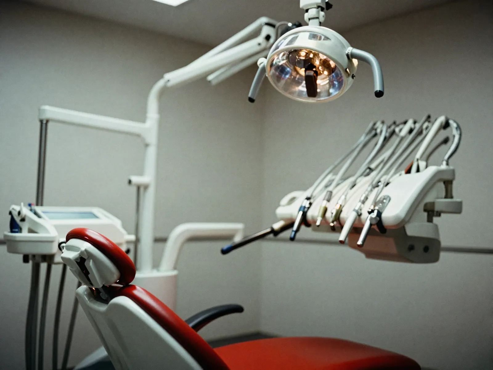 A close crop of a modern dental operatory — the chair and the articulated overhead light arm in clean whites and steel.
