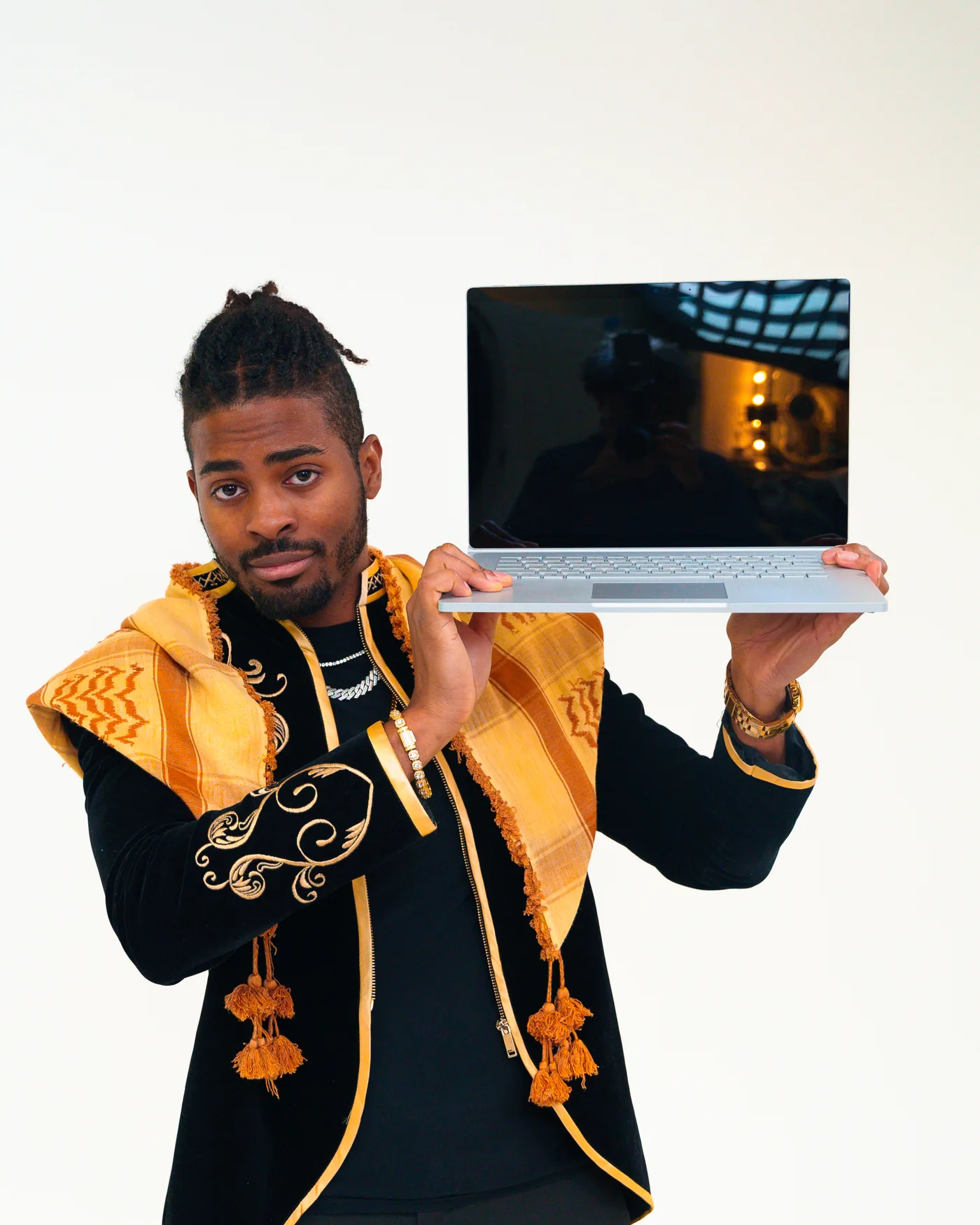 An Agency AF team member in an embroidered black and gold jacket, holding up an open laptop.
